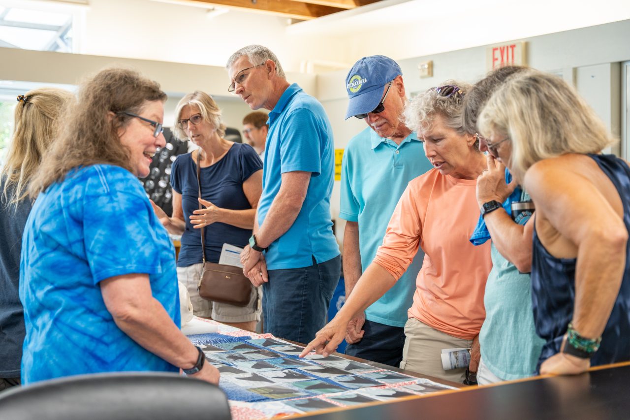 Duke Marine Lab visitors look at photographs of dolphin fins and discuss with researchers during an open house event at the lab.