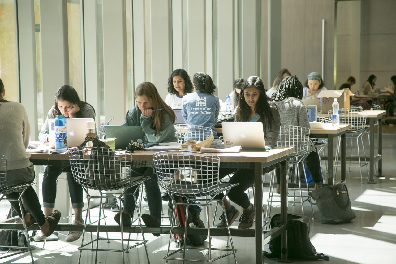 Three tables of students studying independently on their laptops.