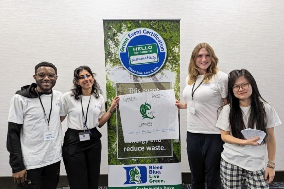 Winners of the Masters Impact Challenge standing for a group photo around a banner that says Bleed Blue, Live Green.