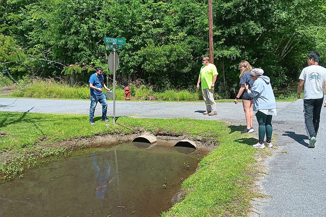 Researchers stand near stormwater culverts and gather data.