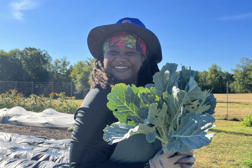 Roo Jackson holding collard greens at Duke Campus Farm.