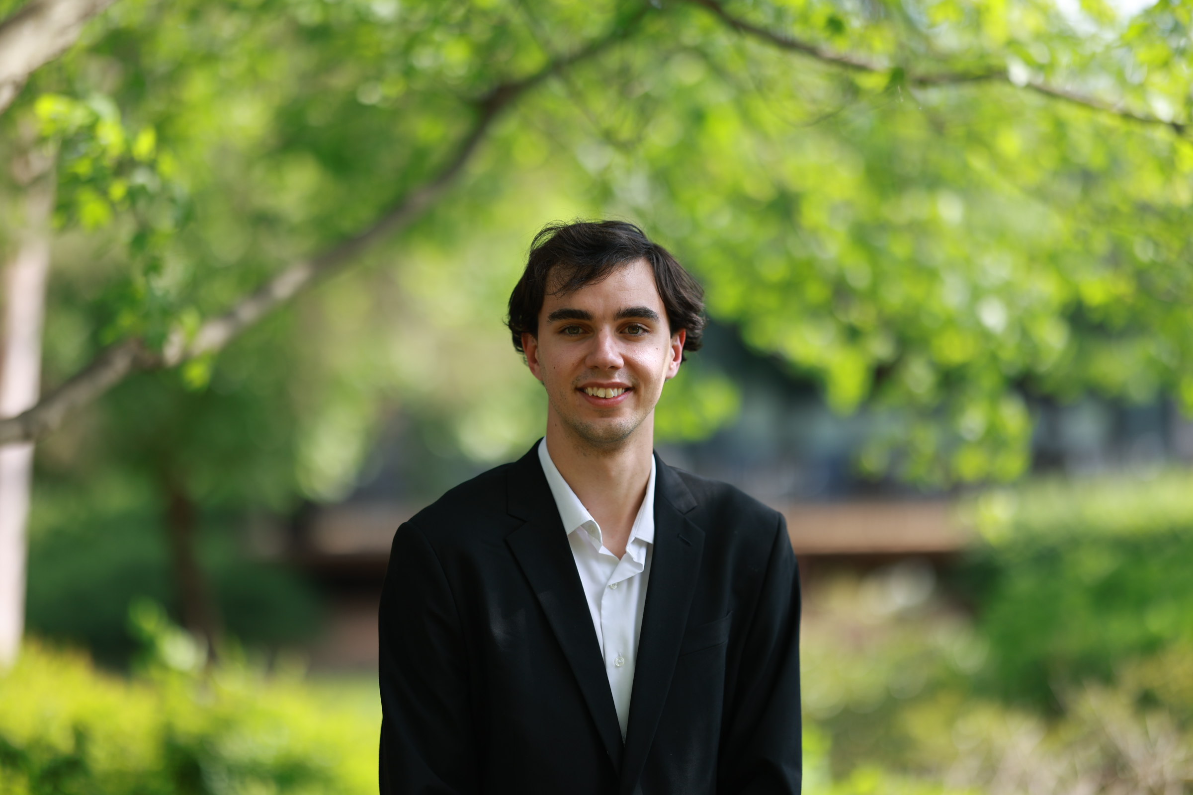 Portrait of Aaron Siegle with trees and campus behind him